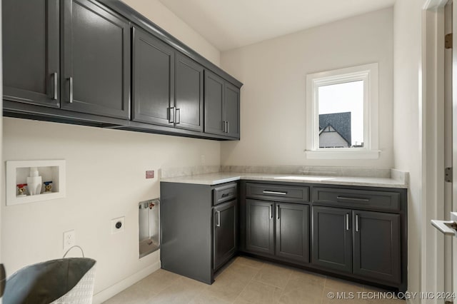 laundry room featuring cabinets, electric dryer hookup, washer hookup, sink, and light tile patterned flooring