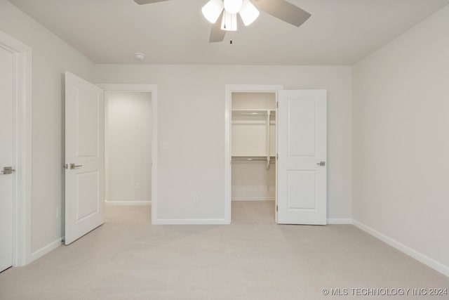 unfurnished bedroom featuring light colored carpet, a spacious closet, ceiling fan, and a closet