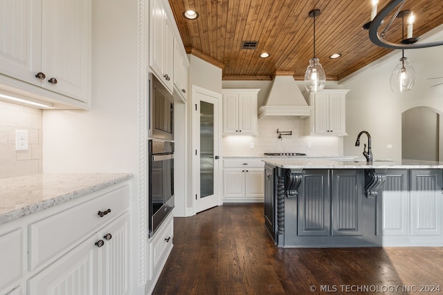 kitchen with hanging light fixtures, white cabinetry, backsplash, dark hardwood / wood-style floors, and custom range hood