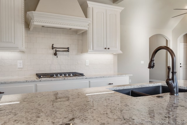 kitchen featuring sink, white cabinets, light stone counters, and tasteful backsplash