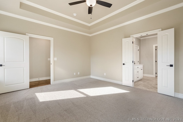 carpeted empty room with ceiling fan, crown molding, and a raised ceiling