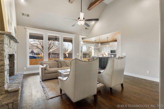 living area featuring a fireplace, visible vents, dark wood-type flooring, a ceiling fan, and high vaulted ceiling