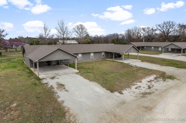 ranch-style home with an attached carport, gravel driveway, roof with shingles, and a front lawn