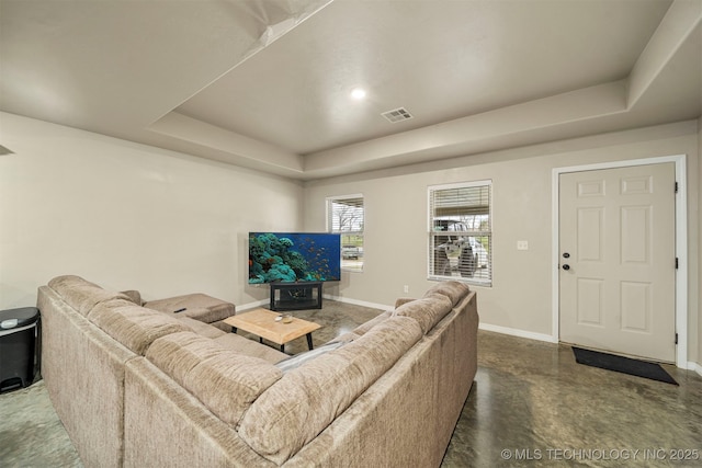 living area featuring finished concrete floors, a raised ceiling, visible vents, and baseboards