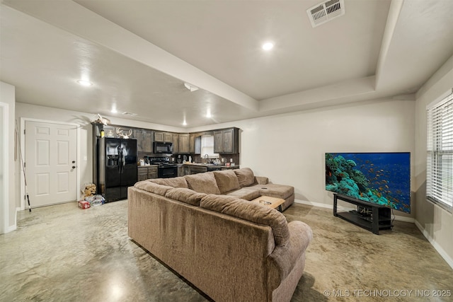 living room with baseboards, visible vents, a tray ceiling, concrete flooring, and recessed lighting