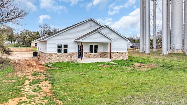 back of property featuring central air condition unit and a yard