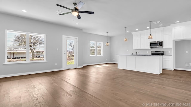 kitchen featuring a healthy amount of sunlight, ceiling fan, dark wood-type flooring, and white cabinetry