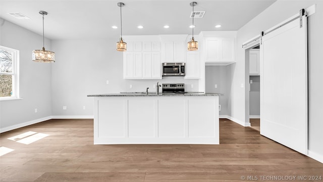 kitchen featuring light hardwood / wood-style floors, a barn door, light stone countertops, white cabinets, and range