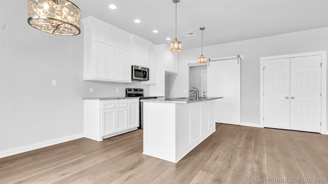 kitchen featuring appliances with stainless steel finishes, white cabinetry, and decorative light fixtures