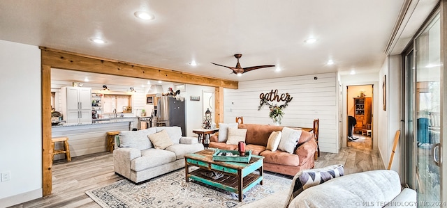 living room featuring wooden walls, sink, light wood-type flooring, and ceiling fan