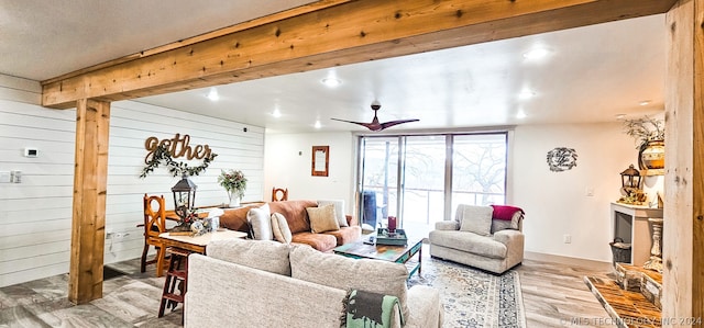 living room featuring ceiling fan, wood walls, and light hardwood / wood-style flooring