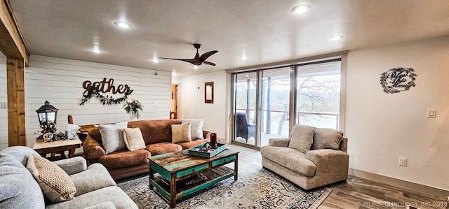 living room with wood walls, hardwood / wood-style floors, and ceiling fan