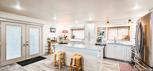 kitchen featuring french doors, stainless steel appliances, sink, a center island, and white cabinetry