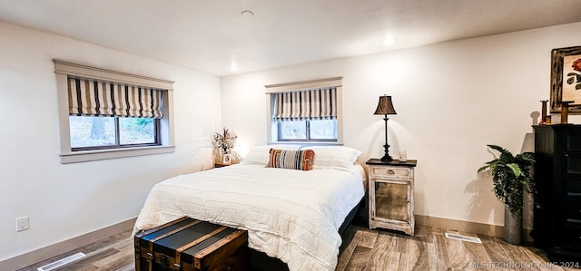 bedroom with multiple windows and hardwood / wood-style flooring