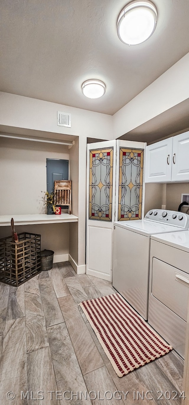 clothes washing area featuring cabinets, a textured ceiling, and washing machine and clothes dryer