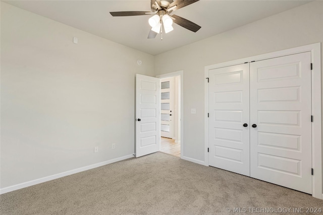 unfurnished bedroom featuring ceiling fan, a closet, and light colored carpet