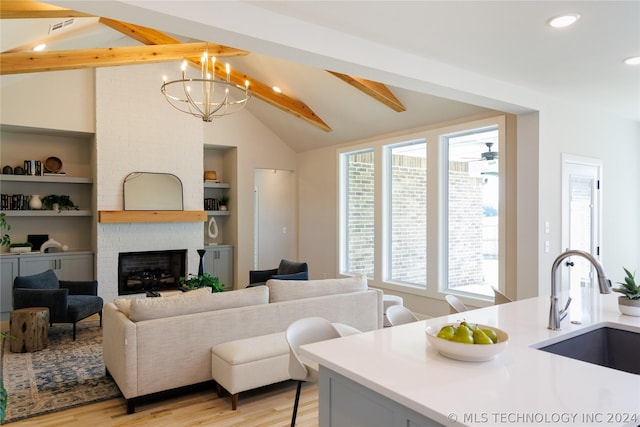 living room featuring sink, a brick fireplace, an inviting chandelier, built in features, and lofted ceiling with beams