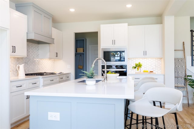 kitchen with white cabinets, an island with sink, and built in microwave