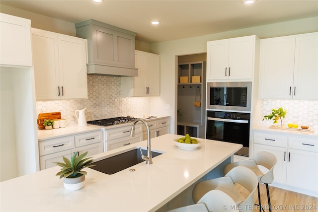 kitchen featuring decorative backsplash, sink, white cabinets, and appliances with stainless steel finishes