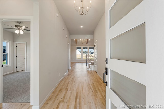 corridor with light carpet and an inviting chandelier