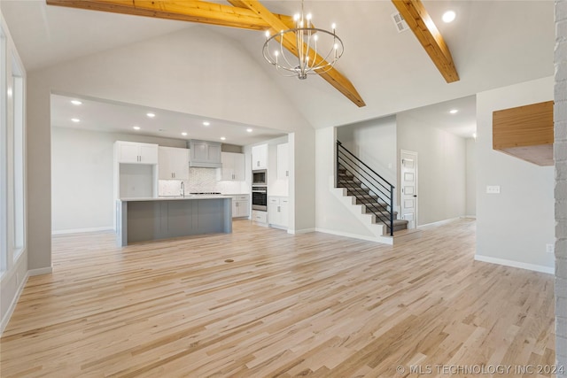 unfurnished living room with beamed ceiling, an inviting chandelier, high vaulted ceiling, and light hardwood / wood-style flooring