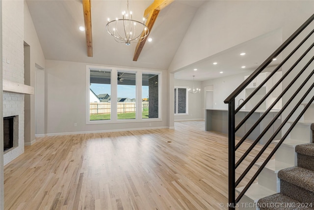 unfurnished living room with a brick fireplace, light hardwood / wood-style flooring, beamed ceiling, high vaulted ceiling, and a notable chandelier