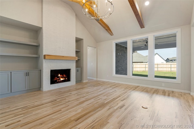 unfurnished living room featuring built in shelves, vaulted ceiling with beams, light hardwood / wood-style flooring, a fireplace, and ceiling fan with notable chandelier