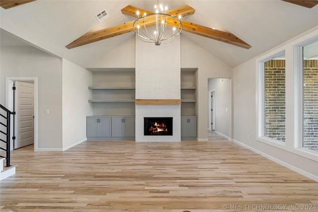 unfurnished living room featuring a chandelier, built in shelves, light wood-type flooring, and a brick fireplace