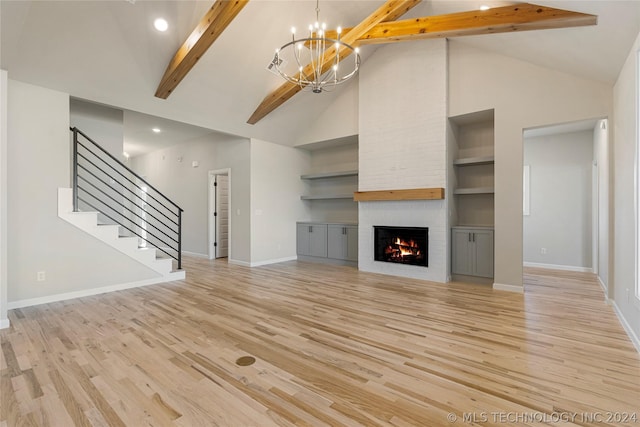 unfurnished living room featuring high vaulted ceiling, built in features, beam ceiling, a large fireplace, and a chandelier