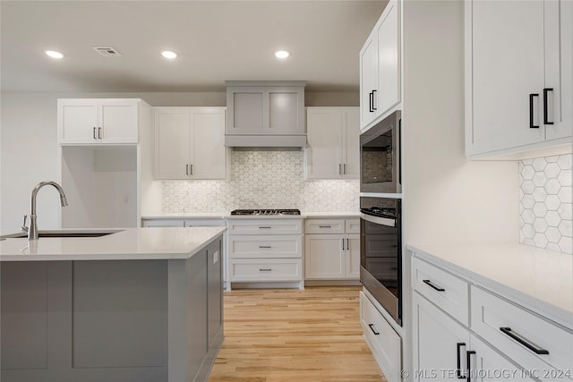 kitchen featuring custom range hood, stainless steel appliances, white cabinetry, and sink