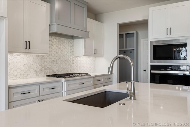 kitchen featuring white cabinets, stainless steel appliances, tasteful backsplash, and sink