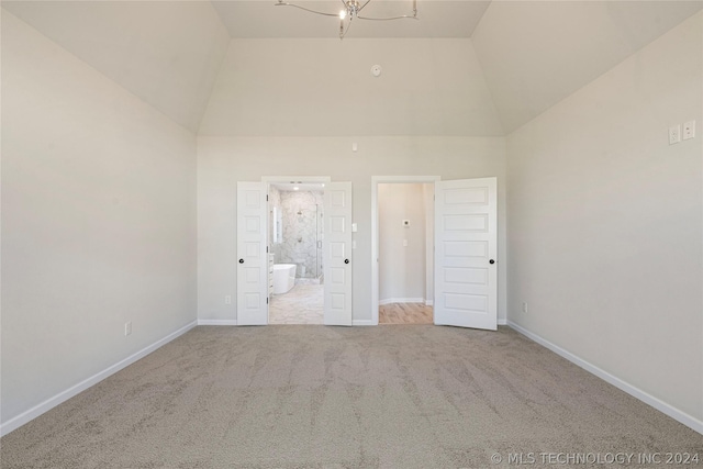 unfurnished bedroom with light carpet, connected bathroom, an inviting chandelier, and high vaulted ceiling