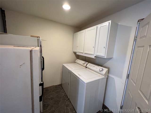 laundry room featuring washer and clothes dryer, dark tile floors, and cabinets