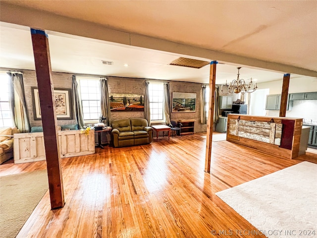 living room with a notable chandelier, beam ceiling, and light hardwood / wood-style floors