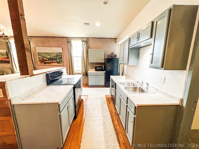 kitchen with tasteful backsplash, gray cabinets, black appliances, and sink