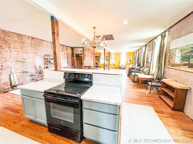 kitchen featuring decorative light fixtures, brick wall, a notable chandelier, light hardwood / wood-style flooring, and black electric range