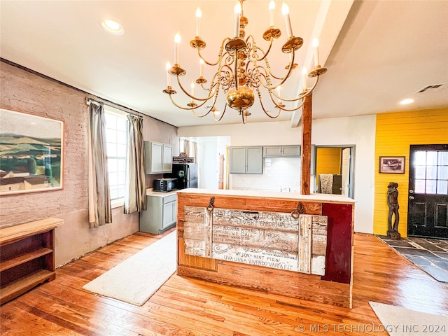 kitchen featuring black refrigerator, a chandelier, gray cabinets, and hardwood / wood-style flooring