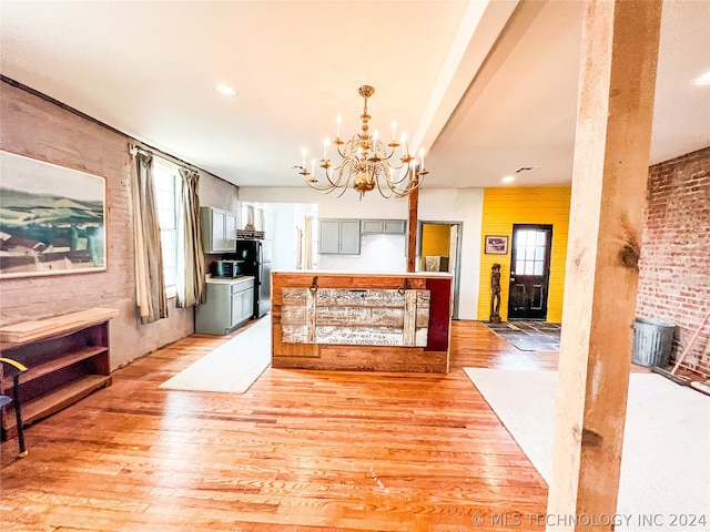 interior space with a chandelier, gray cabinetry, black refrigerator, and light wood-type flooring