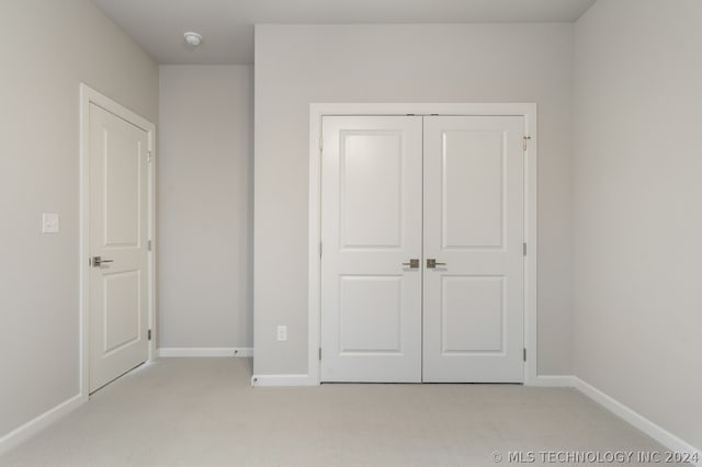 unfurnished bedroom with a closet and light colored carpet