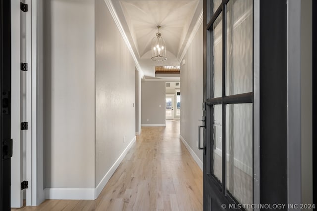 hallway with an inviting chandelier, crown molding, light wood-type flooring, and french doors