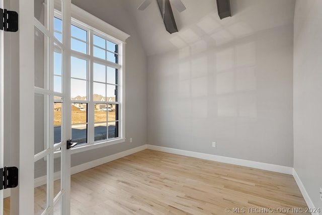 empty room with lofted ceiling with beams, light hardwood / wood-style floors, and ceiling fan