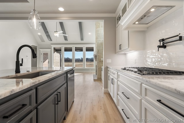 kitchen with tasteful backsplash, light stone counters, light hardwood / wood-style floors, decorative light fixtures, and white cabinetry