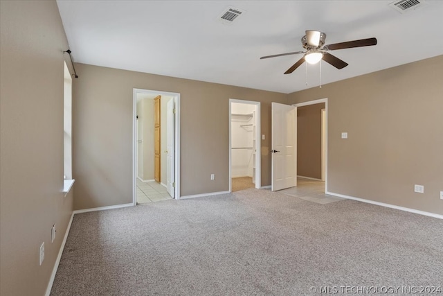 unfurnished bedroom with ceiling fan, a closet, light colored carpet, and a spacious closet