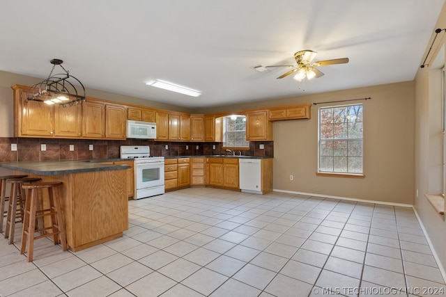 kitchen featuring white appliances, sink, tasteful backsplash, and kitchen peninsula