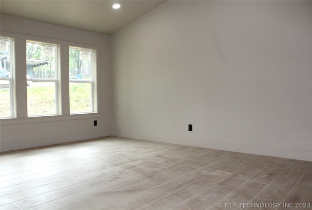 empty room with lofted ceiling and light wood-type flooring