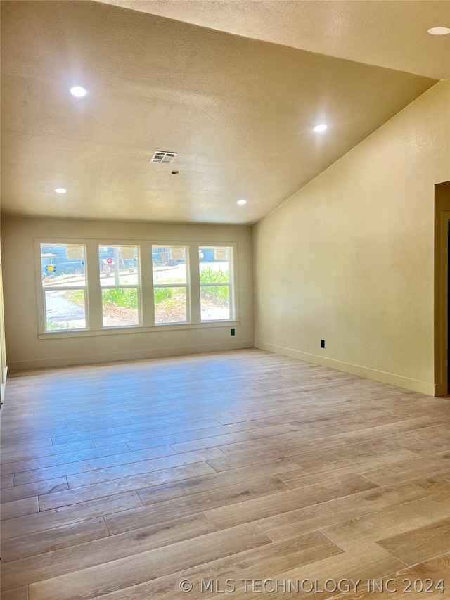 unfurnished room with a textured ceiling and light wood-type flooring