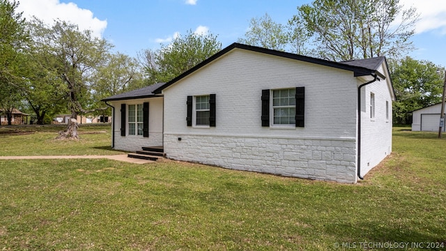 rear view of property with an outdoor structure, a lawn, and a garage