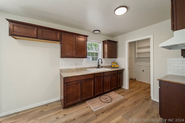 kitchen featuring sink, light hardwood / wood-style floors, dark brown cabinetry, and backsplash