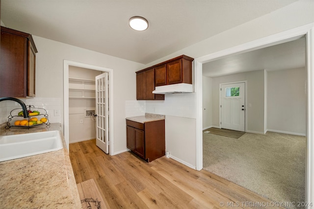 kitchen with sink, light wood-type flooring, and tasteful backsplash