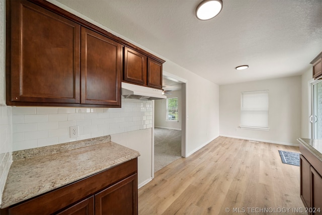 kitchen with backsplash, dark brown cabinetry, light hardwood / wood-style floors, and light stone countertops